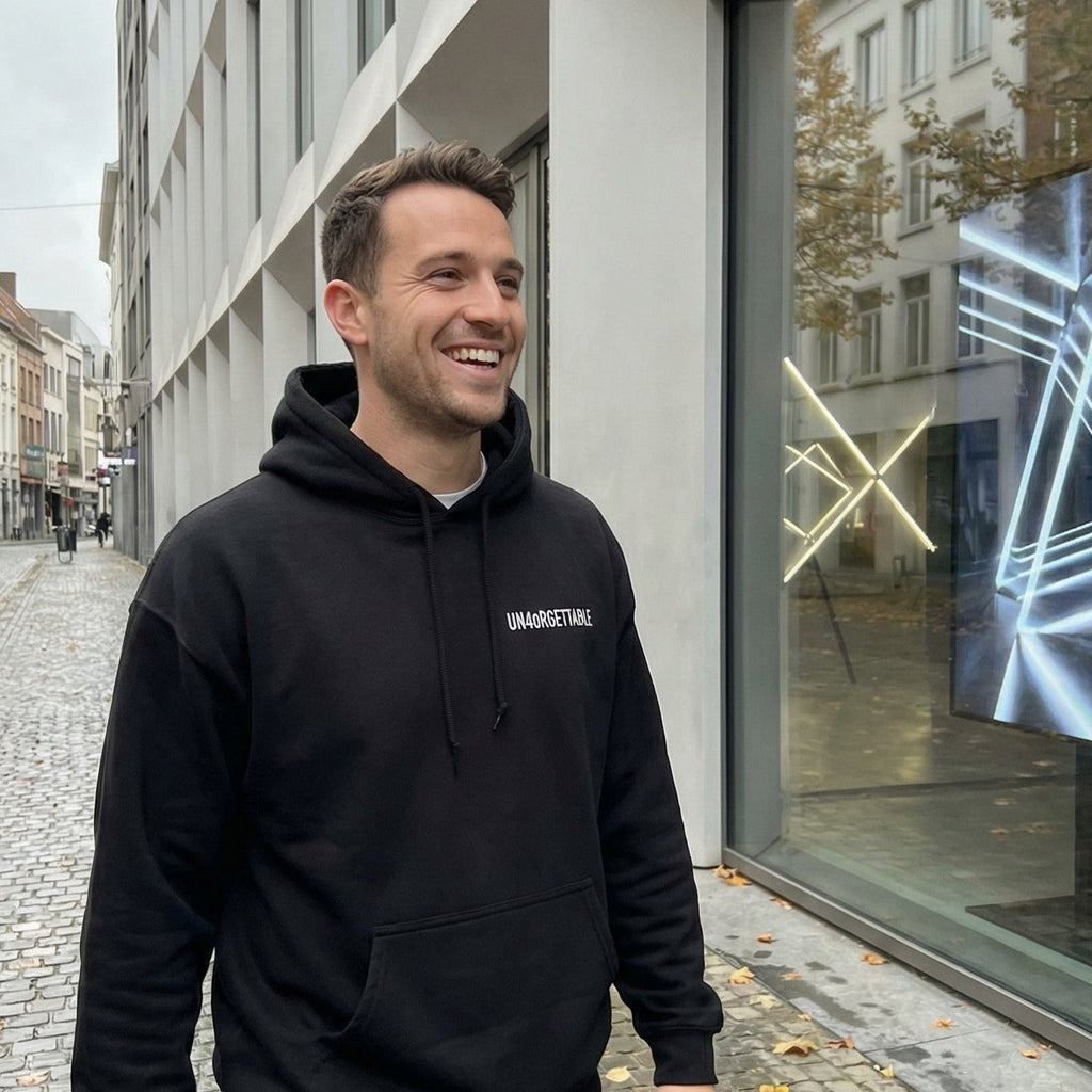 Lächelnder Mann trägt den schwarzen UN4oRGETTABLE Heavy Hoodie für AI Rebels in urbanem Streetwear-Look.